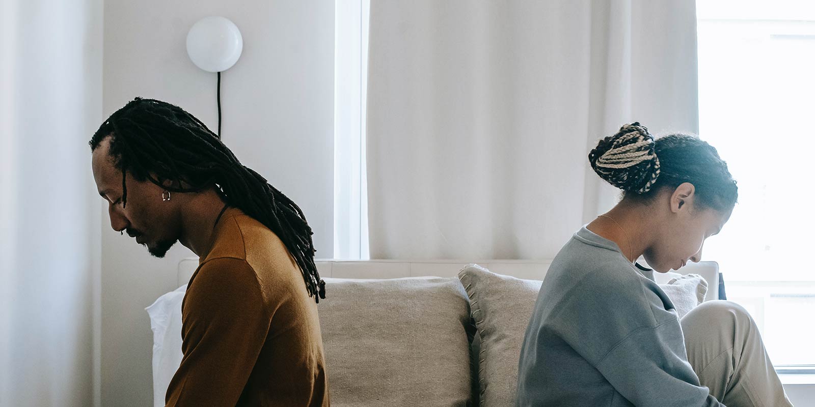 Man and woman on couch have backs to each other
